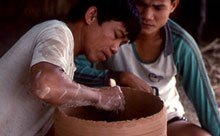 two men working on a clay vessel